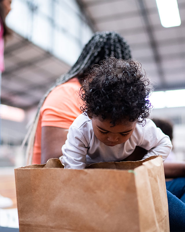 Baby looking into a food bag in a shelter