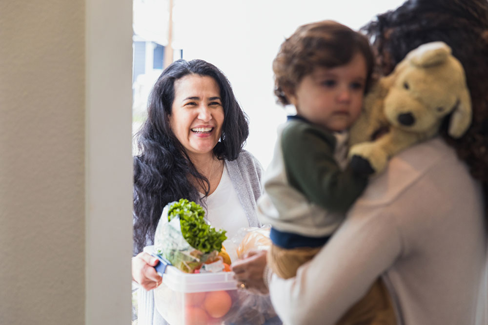 Mature woman gives fresh produce to young adult daughter